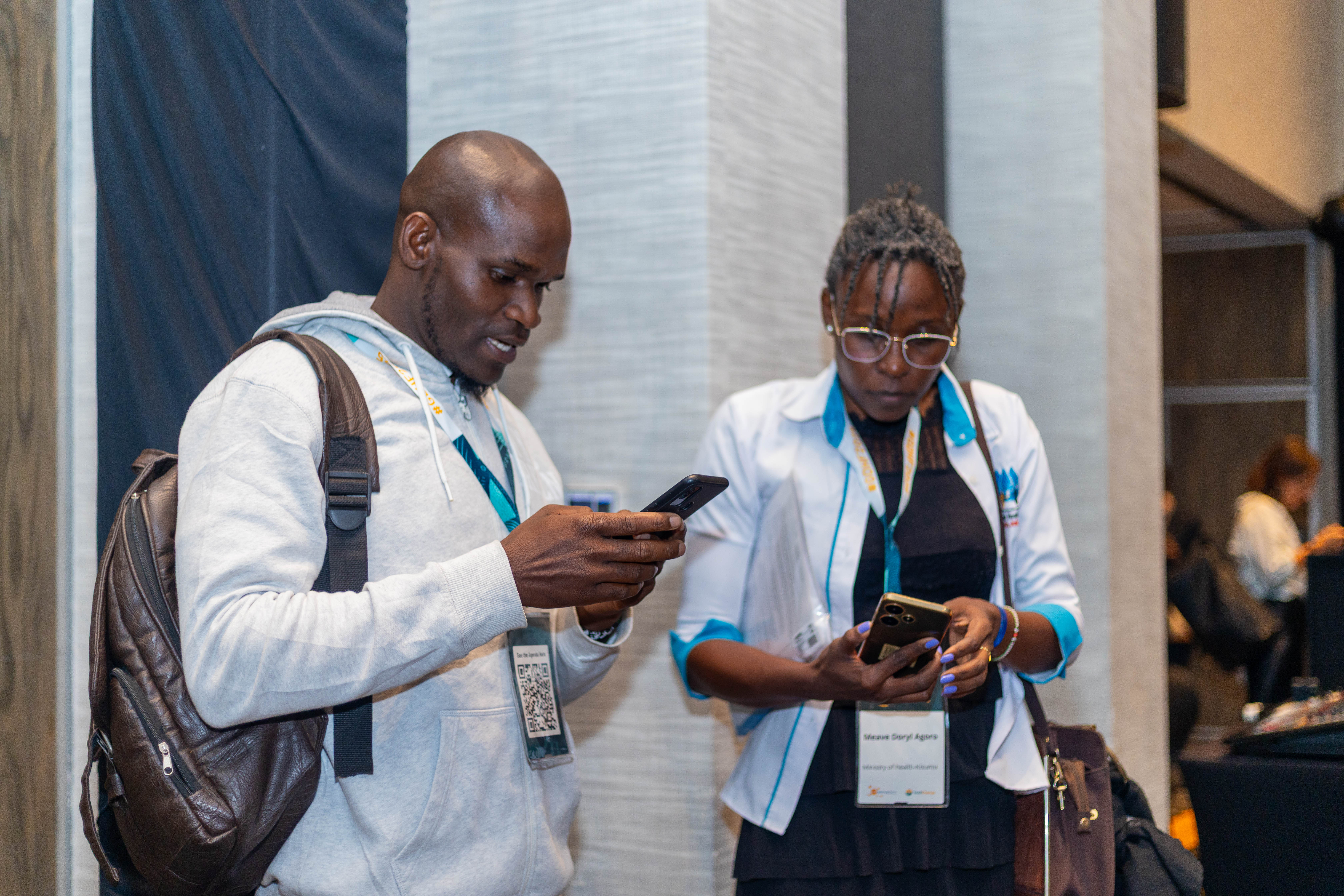 Two conference attendees reviewing information on their phones